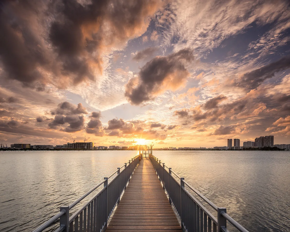 A walkway running out to the horizon beneath a broad, breaking sky.
